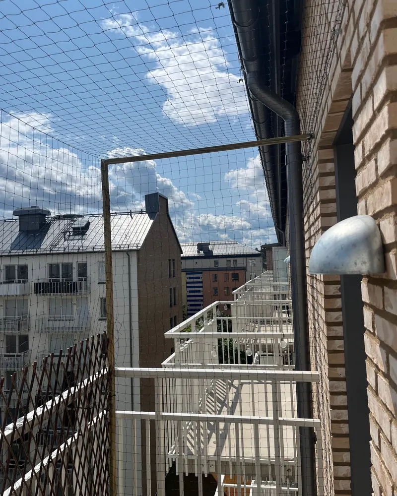 Fågelnät uppspänt över balkongerna på ett flerbostadshus i tegel